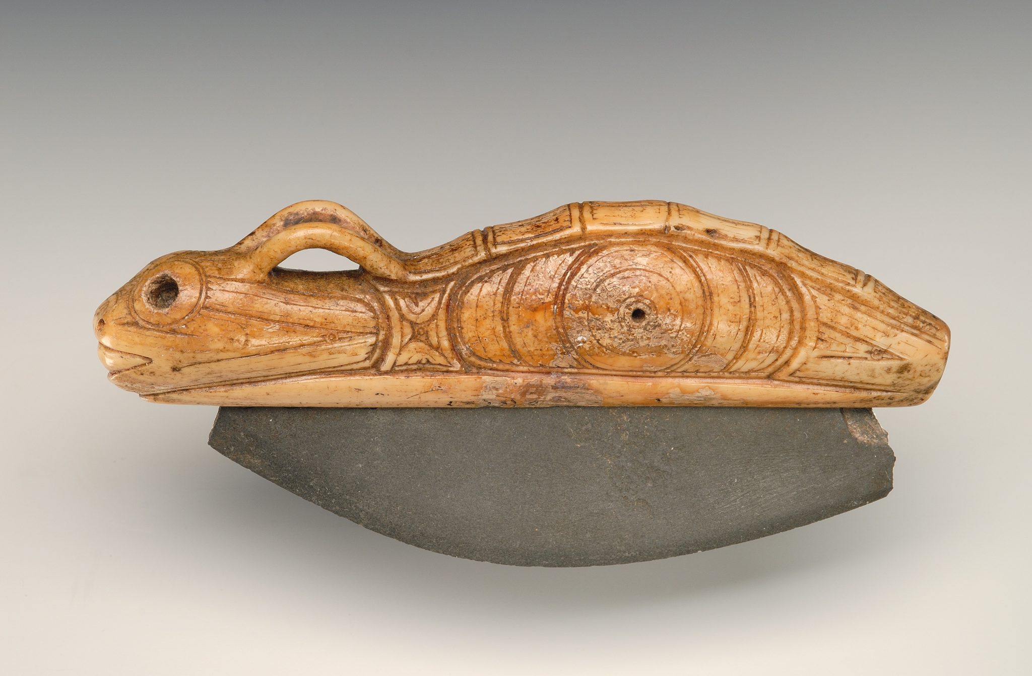 Ulu knife with zoomorphic handle from the ancient Eskimo burial site Ekven (OBS II-III). Material: stone, walrus tusk. State Museum of Oriental Art, Moscow (photo Ye. Zheltov).